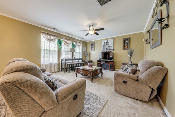 A living room with two beige sofas, a coffee table, a ceiling fan, and a dining area with a table and chairs. - Lakes, Gardens & More! Getaway in Moncks Corner (Moncks Corner)