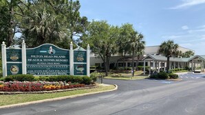 Bordje voor Hilton Head Island Beach & Tennis Resort, met logo van een golfbaan, restaurantlogo en een parkeerplaats.