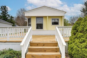 A two-story house with a wooden deck, white railings, and a green bush. - Walk to Silver Lake State Park! Family Getaway (Mears)