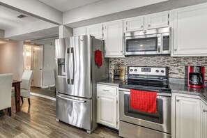 A modern kitchen with stainless steel appliances, white cabinetry, and a dining area with a wooden table and chairs.