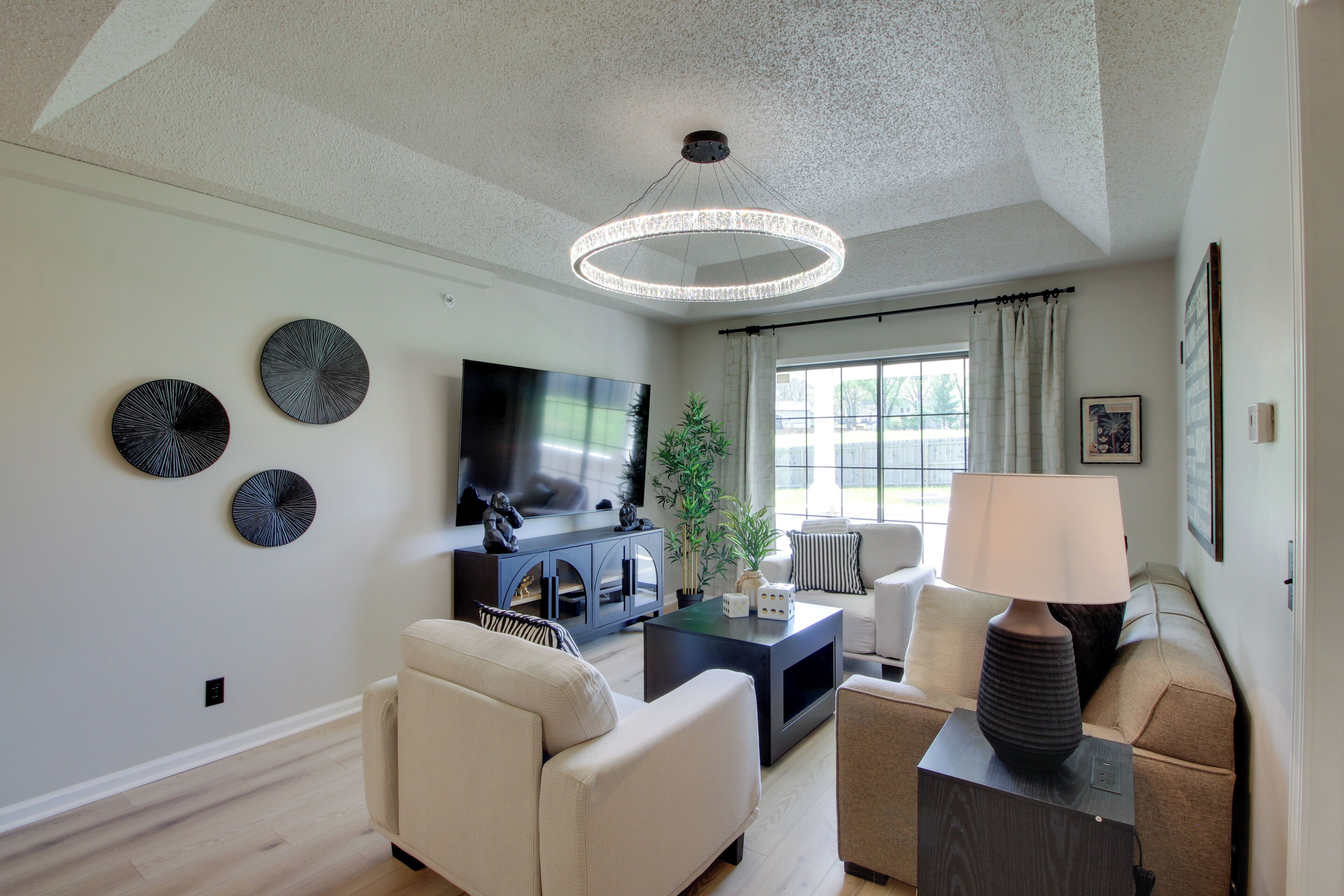 A modern living room with a flat-screen TV, a round ceiling light, and a sofa.