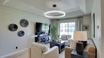 A modern living room with a flat-screen TV, a round ceiling light, and a sofa.