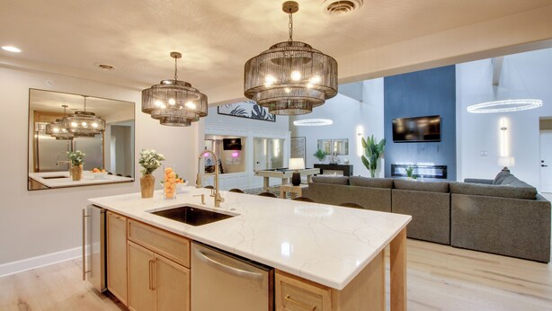 Una cocina moderna con una isla grande, iluminación colgante y un televisor integrado.