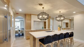 Una cocina moderna con una isla central, armarios de madera e iluminación colgante.