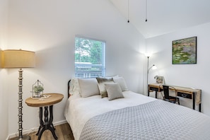A bedroom with a bed, bedside table, lamp, window, desk, chair, and a painting on the wall. - Bring Your Boat! Cozy Home 3 Mi to Sabine River (Joaquin)