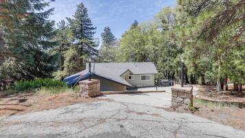 A house with a garage, surrounded by trees, and a driveway leading to the entrance.