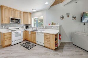 A modern kitchen with wooden cabinets, a microwave, stove, and dishwasher. - Gateway to Big Bear! High-country Home w/ Deck (Running Springs)