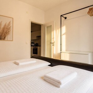 Hotellihuone, jossa on kaksi sänkyä, pieni keittiönurkkaus ja näkymä ulos.