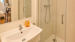 Ein modernes Badezimmer mit einer gläsernen Dusche, einem weißen Waschbecken und einem Spiegel.