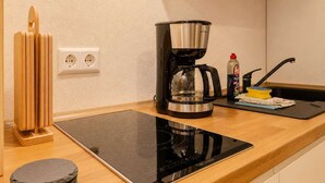 Eine Küche mit Kaffeemaschine, einem Tablet auf der Arbeitsfläche, einem Holz-Küchenhelferhalter und einem Stapel Untersetzer.