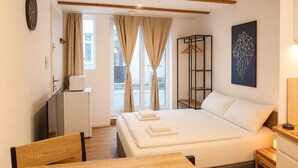 Ein Schlafzimmer mit einem Bett, einem Nachttisch, Holzboden und einem Fenster mit Vorhängen.