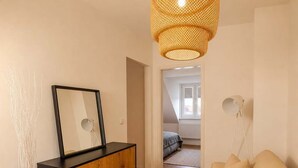 Ett modernt vardagsrum med en soffa, ett skåp, en spegel och en hängande lampa.