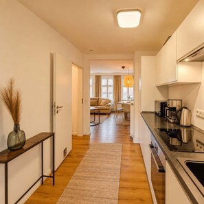 A modern kitchen with a built-in stove, a coffee maker, and a kettle on the counter. - Spacious Maisonette in the Heart of Wismar (Wismar)