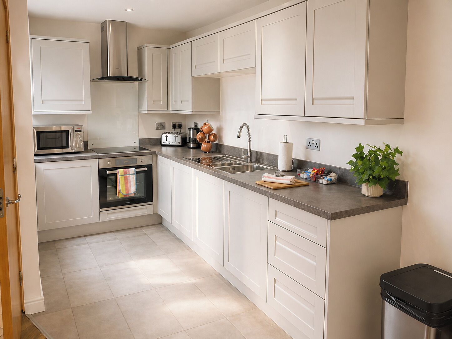 A modern kitchen with white cabinets, stainless steel appliances, and a grey countertop.