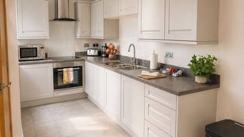 A modern kitchen with white cabinets, stainless steel appliances, and a grey countertop.