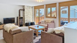 Ein gemütliches Wohnzimmer mit Kamin, bequemen Sitzgelegenheiten und großen Fenstern.