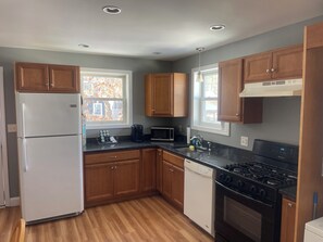 A kitchen with wooden cabinets, a refrigerator, a dishwasher, a stove, and a microwave. - 2-bedroom lakeside retreat in beautiful Windham (Windham)