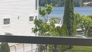A residential street with a white building, a road, and a body of water in the background.