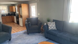 A living room with a grey sofa, a wooden coffee table, and a grey rug.