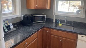 A kitchen with wooden cabinets, a microwave, a coffee maker, and a sink.