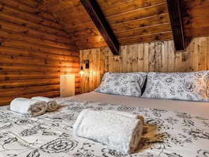 Ein Holzhütten-Innenraum mit einem Bett, Kissen und einer Wandleuchte.