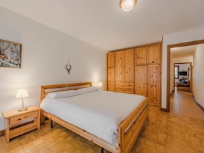 Ein Schlafzimmer mit einem Holzbett, Nachttischen, einer Wandleuchte und einem Holzschrank.