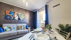 Ein Essbereich mit einem für zwei Personen gedeckten Tisch, einer Couch mit gemusterten Kissen und Kunstwerken an der Wand.