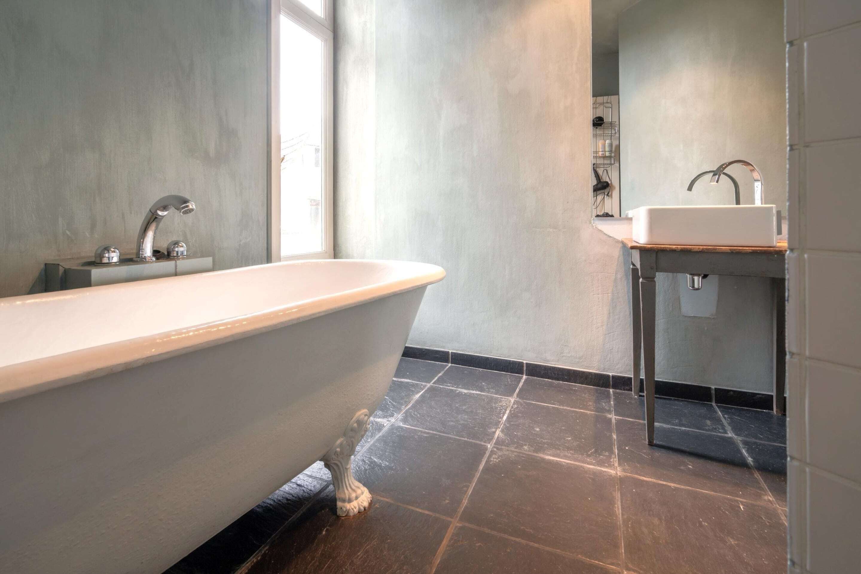 Un baño moderno con una bañera independiente, un lavabo con un grifo moderno y un suelo de baldosas.