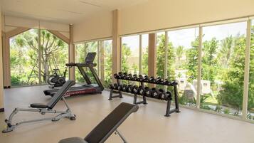 A gym with exercise equipment, large windows, and a view of greenery.