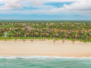 A coastal resort with beach umbrellas, palm trees, and beachfront villas. - Carabeach Retreat (Cam Ranh)