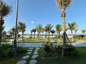 A pathway leading to a beach with palm trees and a clear sky.