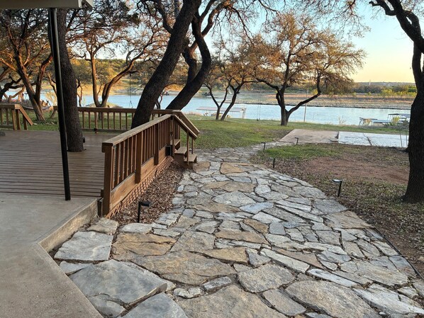 A stone pathway leading to a wooden deck with a view of a lake. - Lake Travis waterfront escape that sleeps 16 (Spicewood)