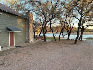 A building with a stone chimney, a wooden door, and a gravel driveway. - Lake Travis waterfront escape that sleeps 16 (Spicewood)