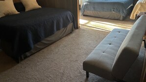 Ein Schlafzimmer mit zwei Betten, einer Schlafcouch und Teppichboden.