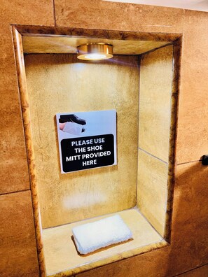 Een toiletruimte met een bordje dat vraagt om de schoenbeschermer te gebruiken.