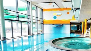 An indoor swimming pool with clear glass walls, a hot tub, and a colorful mural on the wall. - Moderne Ferienwohnung mit Meerblick (Fehmarn)