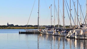 A marina with multiple sailboats docked, calm water, and a distant building. - Moderne Ferienwohnung mit Meerblick (Fehmarn)