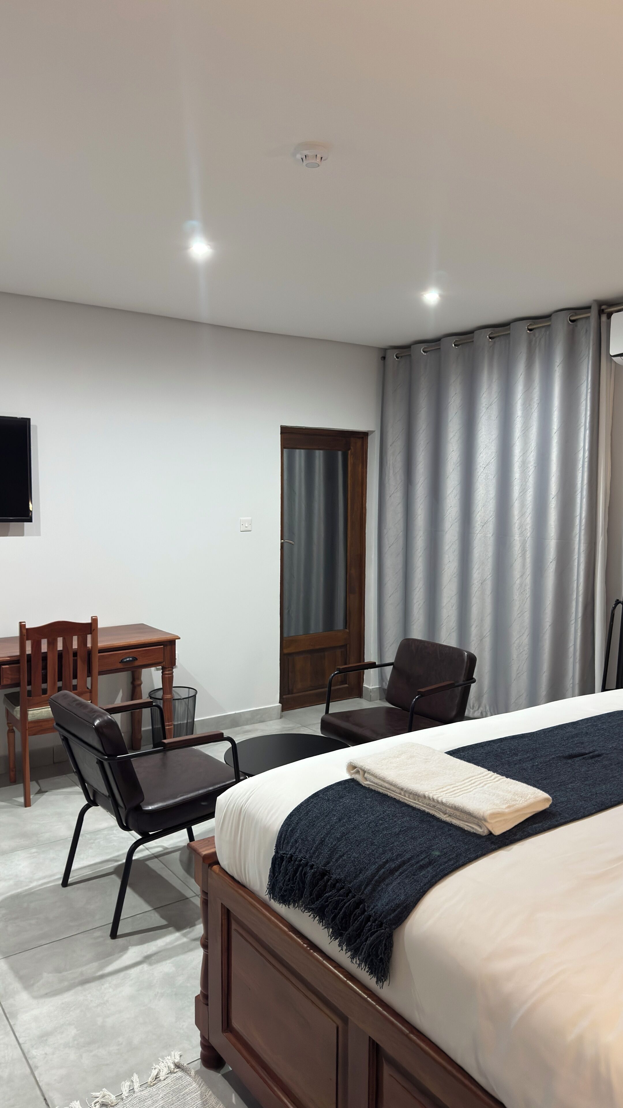 Un dormitorio con cama, escritorio, silla y puerta.