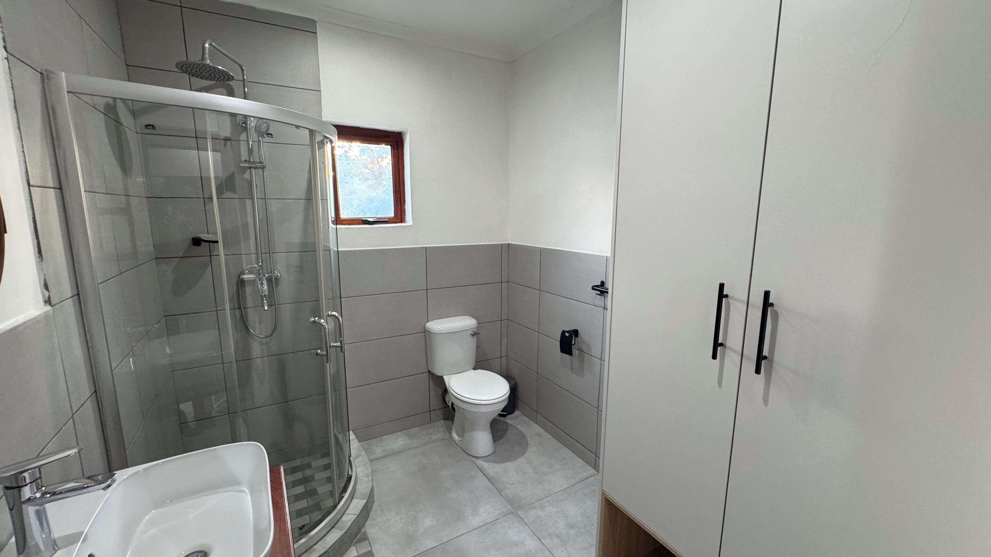 Un baño con ducha de vidrio, inodoro y lavamanos.