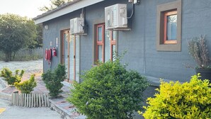 A building with air conditioning units, a fire hose reel, and potted plants. - Raintree Hotel (Nata)