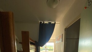 Ein schmaler Korridor mit Holzboden, einem Etagenbett links und einem Badezimmer rechts.