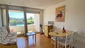 Ein Wohnzimmer mit Sofa, einem kleinen Tisch, einem Esstisch mit Stühlen, einem Ventilator und einem Fernseher.