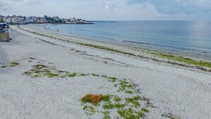 A beach with a sandy shore, a clear sky, and a distant shoreline with buildings. - Oceanfront Escape for 7 in Audierne (Audierne)