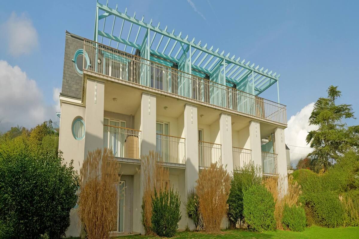 Un edificio de varios pisos con balcón, ventanas amplias y jard ín.