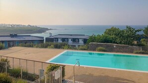 A swimming pool with a view of the sea, surrounded by buildings with a metal roof. - Oceanfront Escape for 7 in Audierne (Audierne)