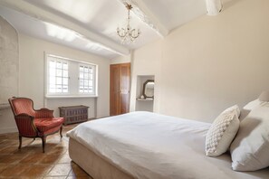 A bedroom with a large bed, a chair, a dresser, and a window. - Uzes, Place aux Herbes, Penthouse Le Belvedere , 360 city view Rooftop et clim (Uzès)