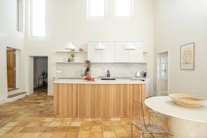 A modern kitchen with a central island, white cabinets, and pendant lighting. - Uzes, Place aux Herbes, Penthouse Le Belvedere , 360 city view Rooftop et clim (Uzès)