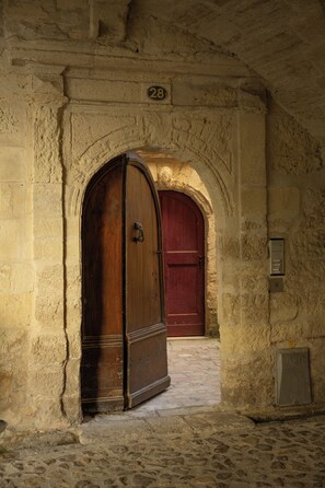 An arched doorway with a wooden door, a stone wall, and a number '28' sign. - Uzes, Place aux Herbes, Penthouse Le Belvedere , 360 city view Rooftop et clim (Uzès)