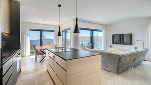 A modern kitchen with a dining area, a sofa, and a TV. - Luxury apartment with stunning sea views (Seget Vranjica)