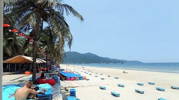 A beach with blue benches, a covered seating area, and palm trees. - Aroma-Pool-Breakfast-Man Thai beach (Da Nang)